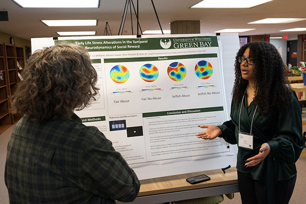 Young woman explaining her research poster to an onlooker