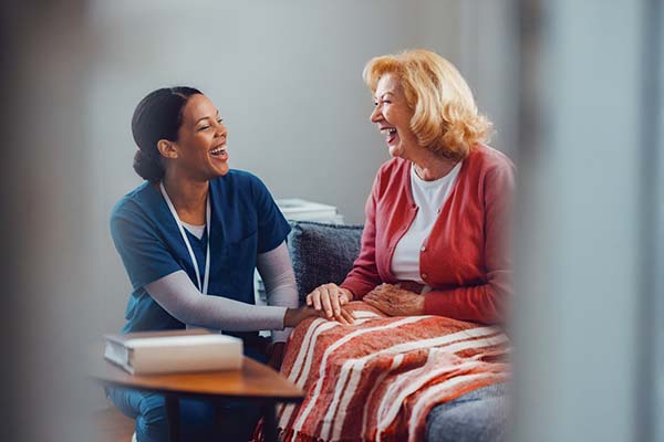 happy CNA smiling while talking to resident at assisted living