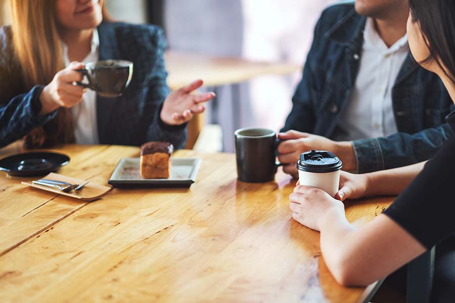 close up of people meeting holding coffee cups