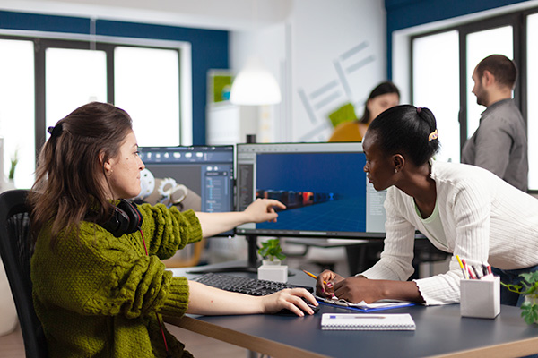 Two women in an office discussing image on computer