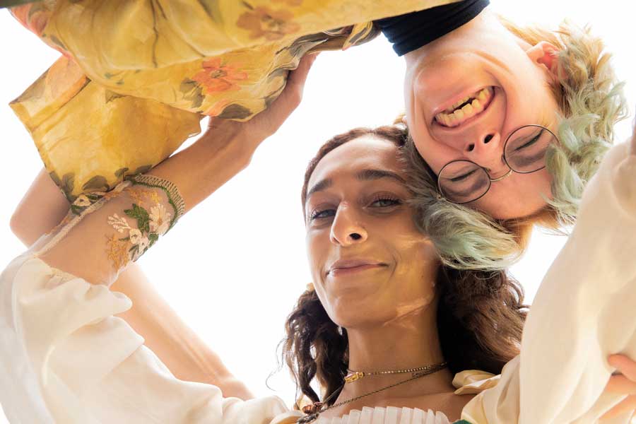 Two students embrace while looking down at camera