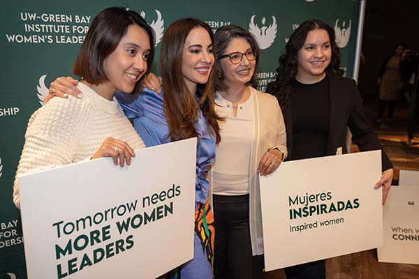 four women holding signs in photo booth