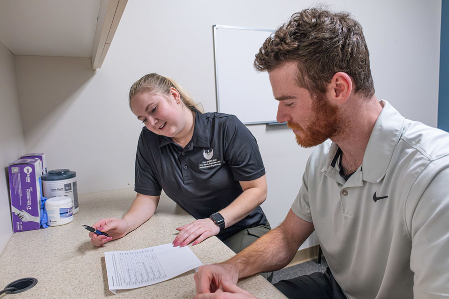 Two adults in an office, reviewing an exercise program
