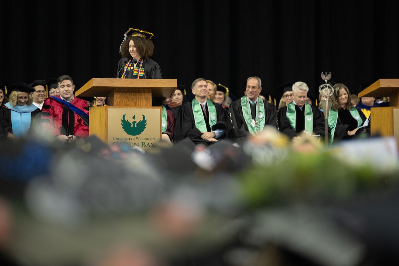 A student commencement speaker addresses the crowd from stage