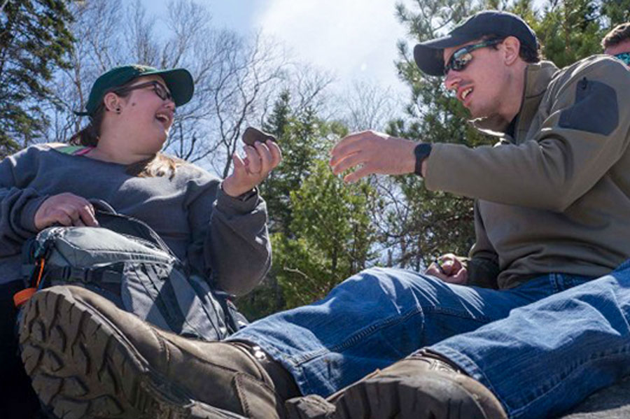 Two students sitting outside looking at rock