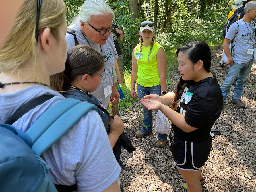 Person showing something to students at camp