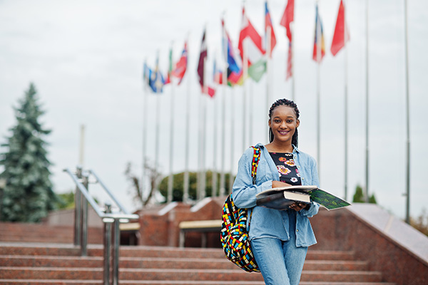 Woman with books in front of several foreign flags