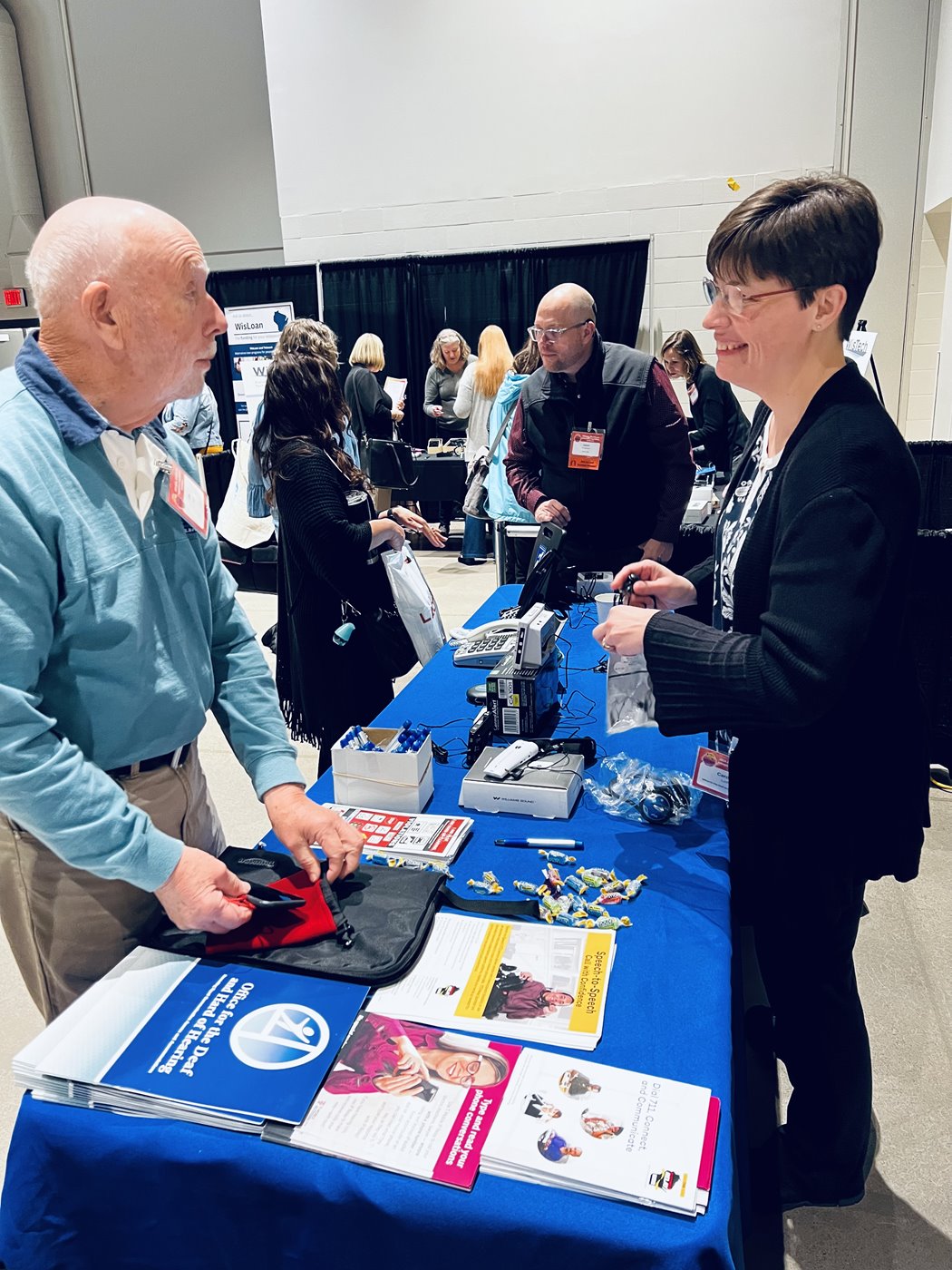 Two people discussing assistive technology at an expo table.