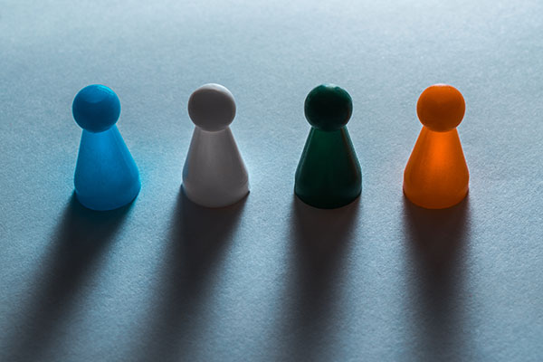 four brightly colored meeple game pieces