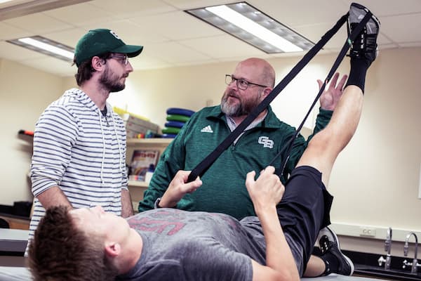 Professor teaching students stretches in lab