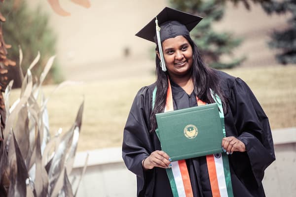 Female student poses with diploma after graduation
