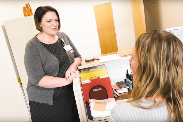 Graduate Nicole Swanson chats in office with coworker