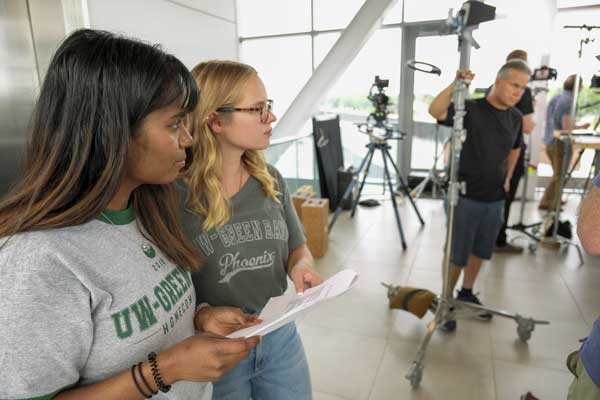 Two students work behind the scenes for marketing project