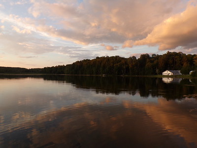 Photo of a sunset sky over a lake house.