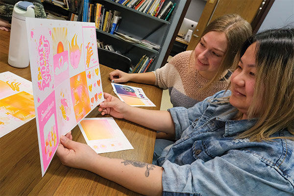 Two students look over printed Risograph Valentines.