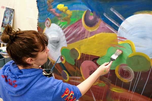 Student painting a large canvas