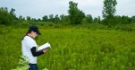 Student in a field taking notes