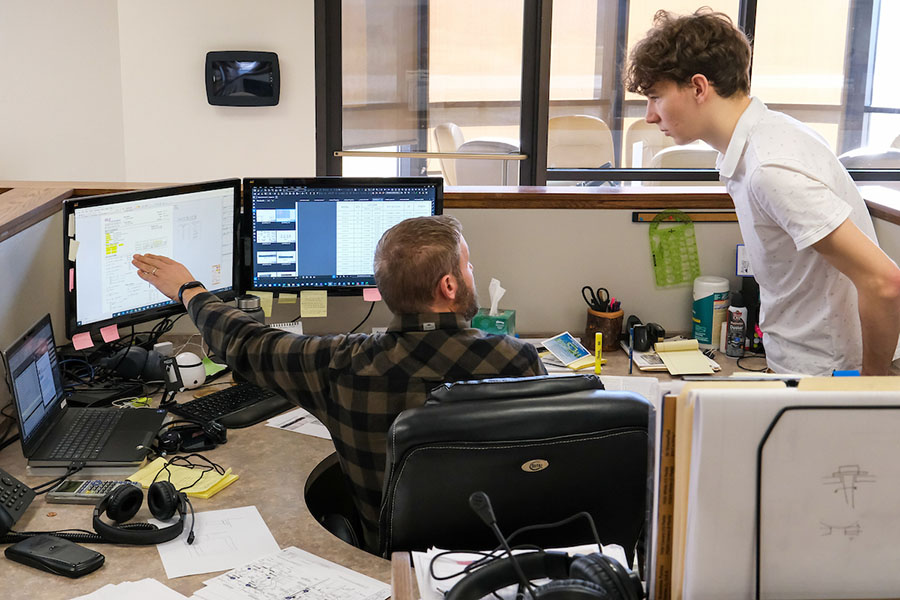 Young man working with mentor in office cubicle