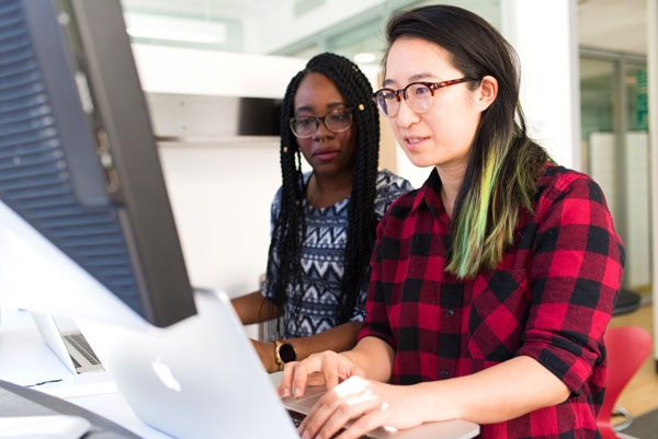 Two female data science students study at computer