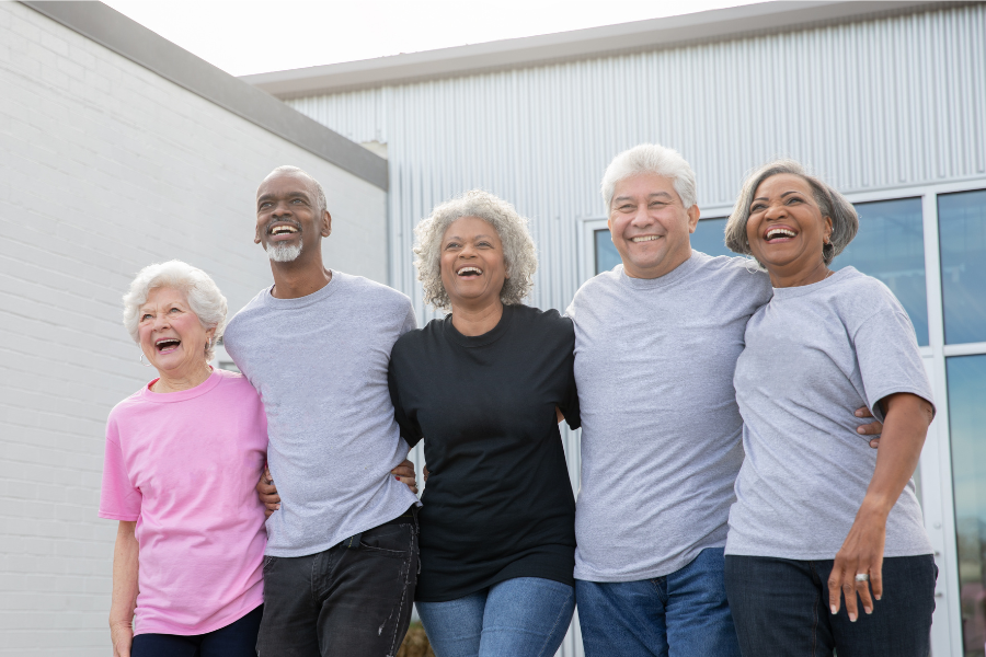 Diverse group of five happy older adults walking arm in arm