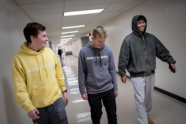 Three male students walking in campus hallway