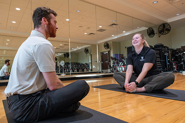Two adults on yoga mats in exercise room
