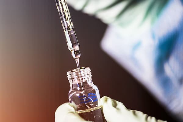 scientist uses glass stirring bar to mix liquid in vial