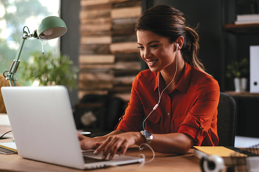 A woman with earbuds in on her computer