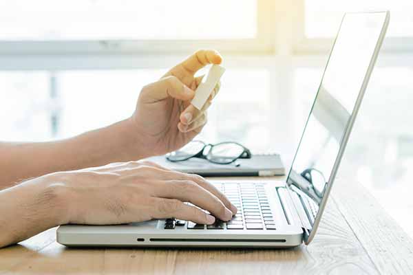 closeup of hand using laptop to register with a credit card