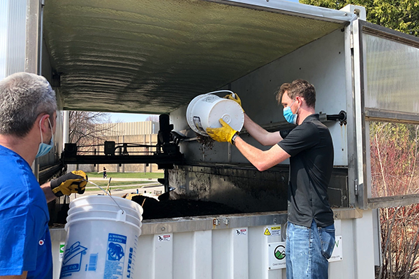 Student and faculty member add to compost