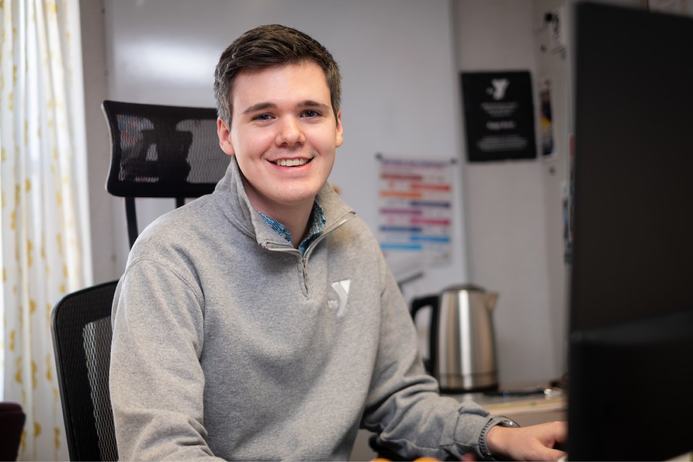 UWGB alumni Gage Beck sits at his desk at the YMCA