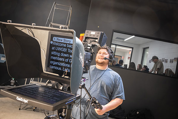 Student operating TV studio camera with teleprompter