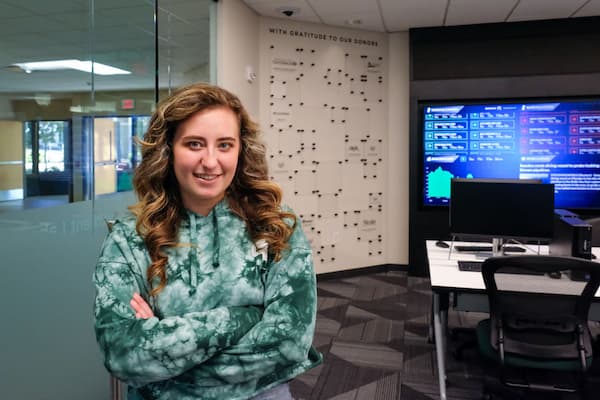Video still of female student posing with crossed arms in finance lab