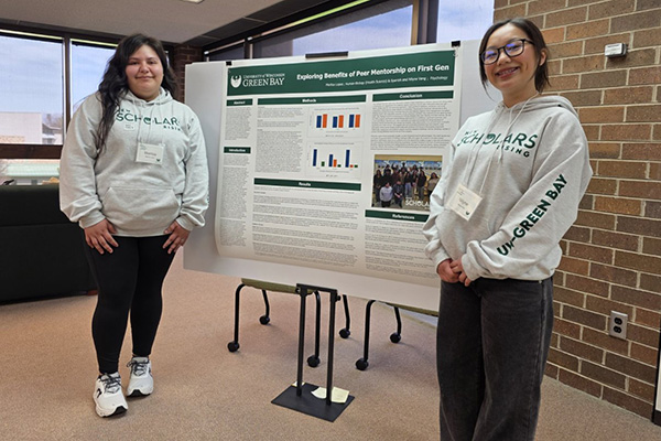 Two students in front of large informational poster