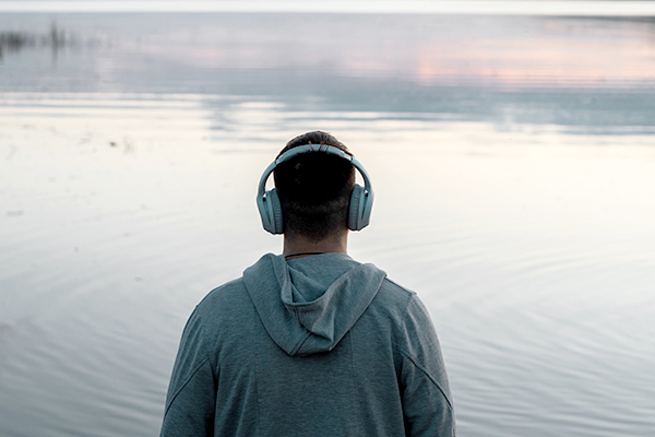 Young man outdoors by water with headphones