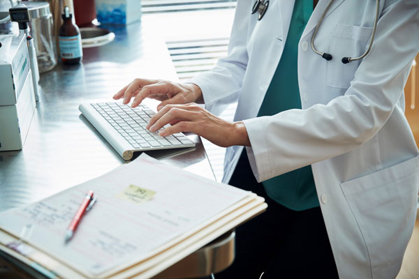 Healthcare worker types at desk