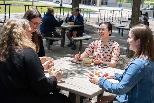 UWGB staff taking a lunch break outside at a campus picnic table