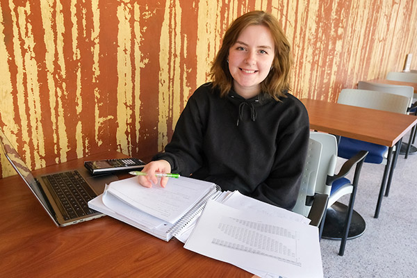 Student studying at table with laptop and notebooks