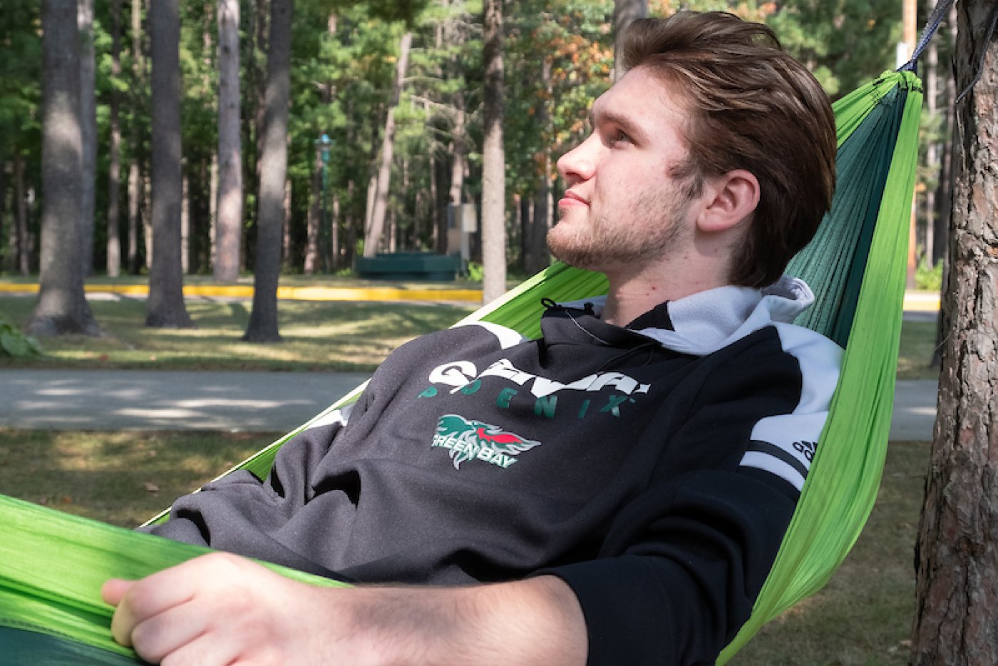 A male student relaxes in a hammock on the Marinette campus.