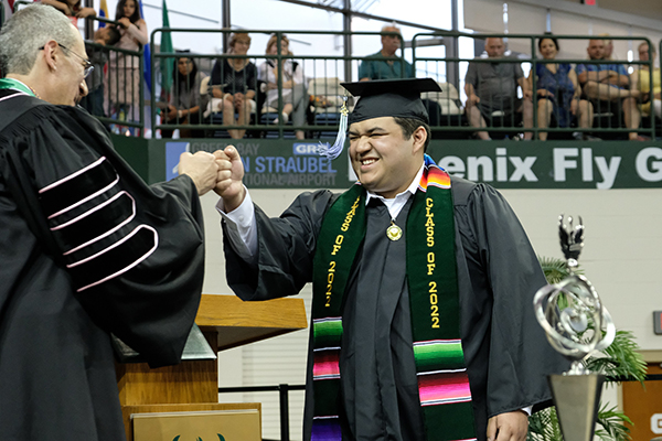 student fist-bumping the Chancellor at Commencement