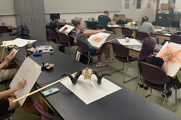 Students working at tables in a drawing class.