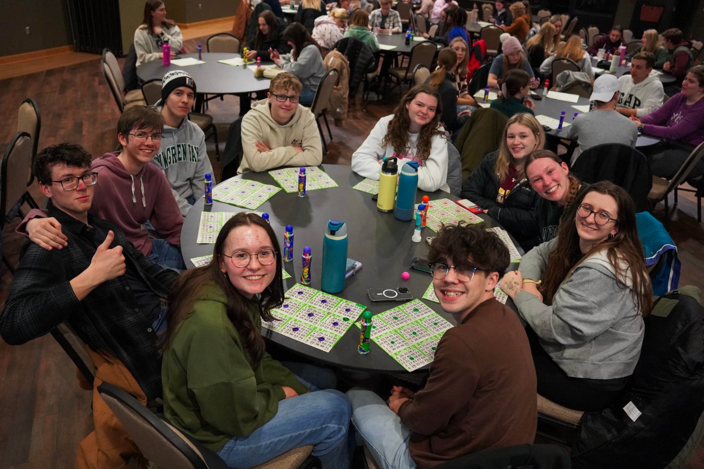 A group of 10 students sit around a table and play Bingo