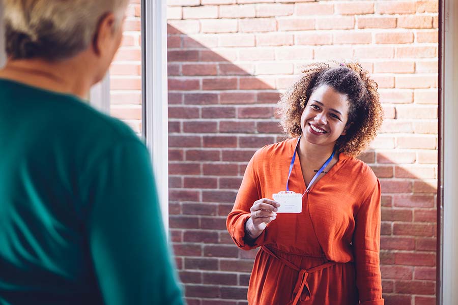 smiling social worker greeting person at their front door